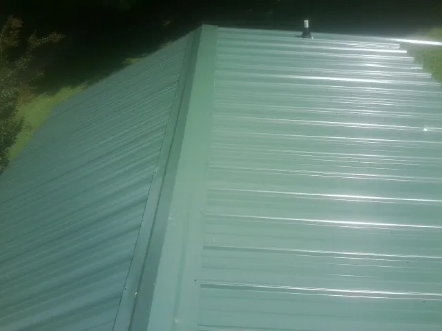 New green metal panels meeting at the ridge of a roof — Flat Roof Repair work by our crew in St Columbans