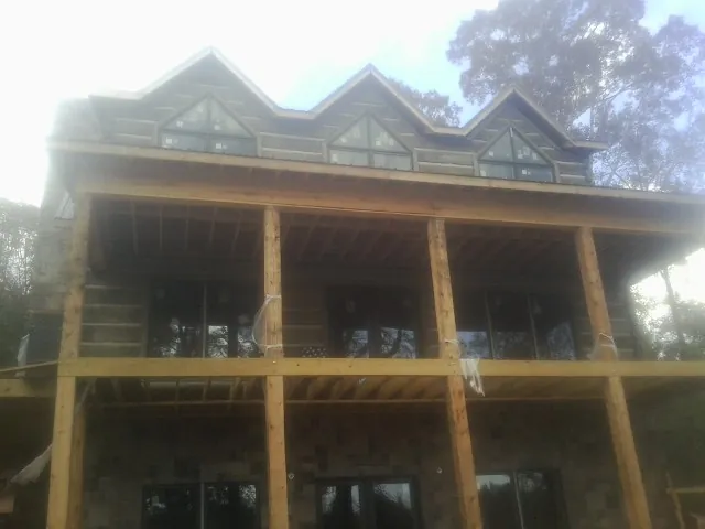 Dormers and porch framing on a large log home under construction — Roof Coating work by our crew in St Columbans