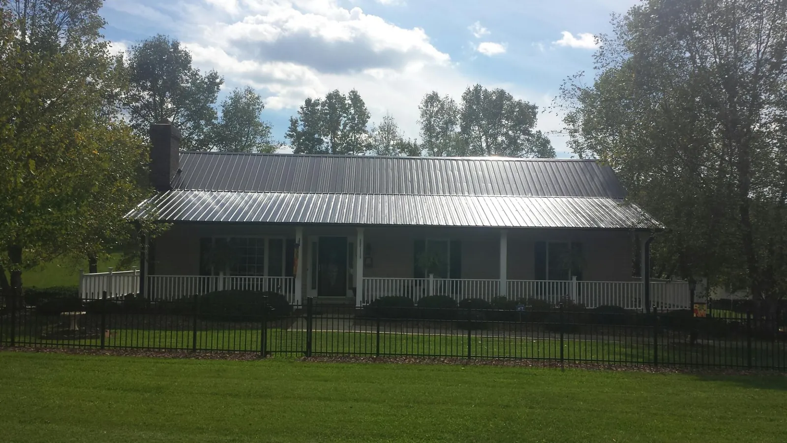 Gray metal roof on a brick ranch with a full width front porch — Gutter Guard Installation work by our crew in St Columbans