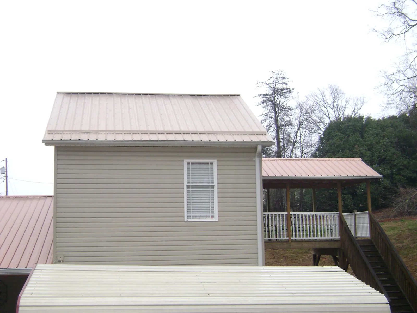 Tan metal roofs on a two story addition and attached porch, from a Roof Replacement job in St Columbans