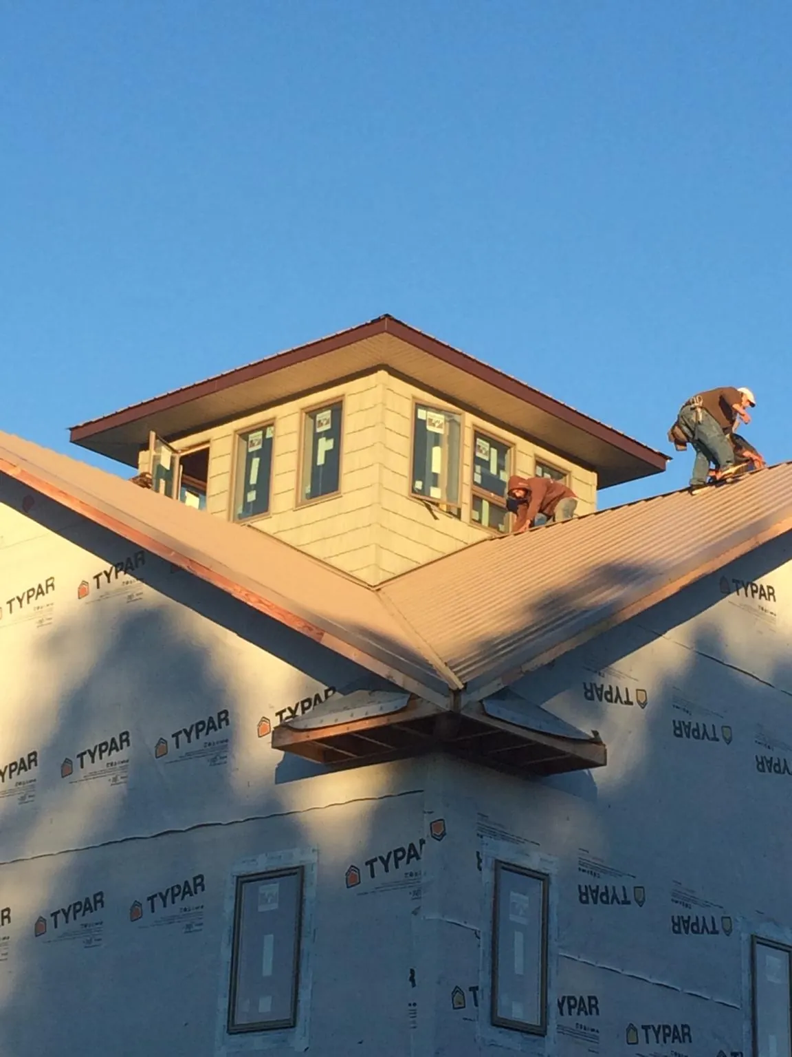 Roofers working around a rooftop cupola on a new metal roof at sunset — Roof Waterproofing in St Columbans by Roofing Brothers